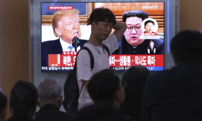 People watch a TV screen showing Donald Trump, left, and Kim Jong Un