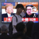 People watch a TV screen showing Donald Trump, left, and Kim Jong Un