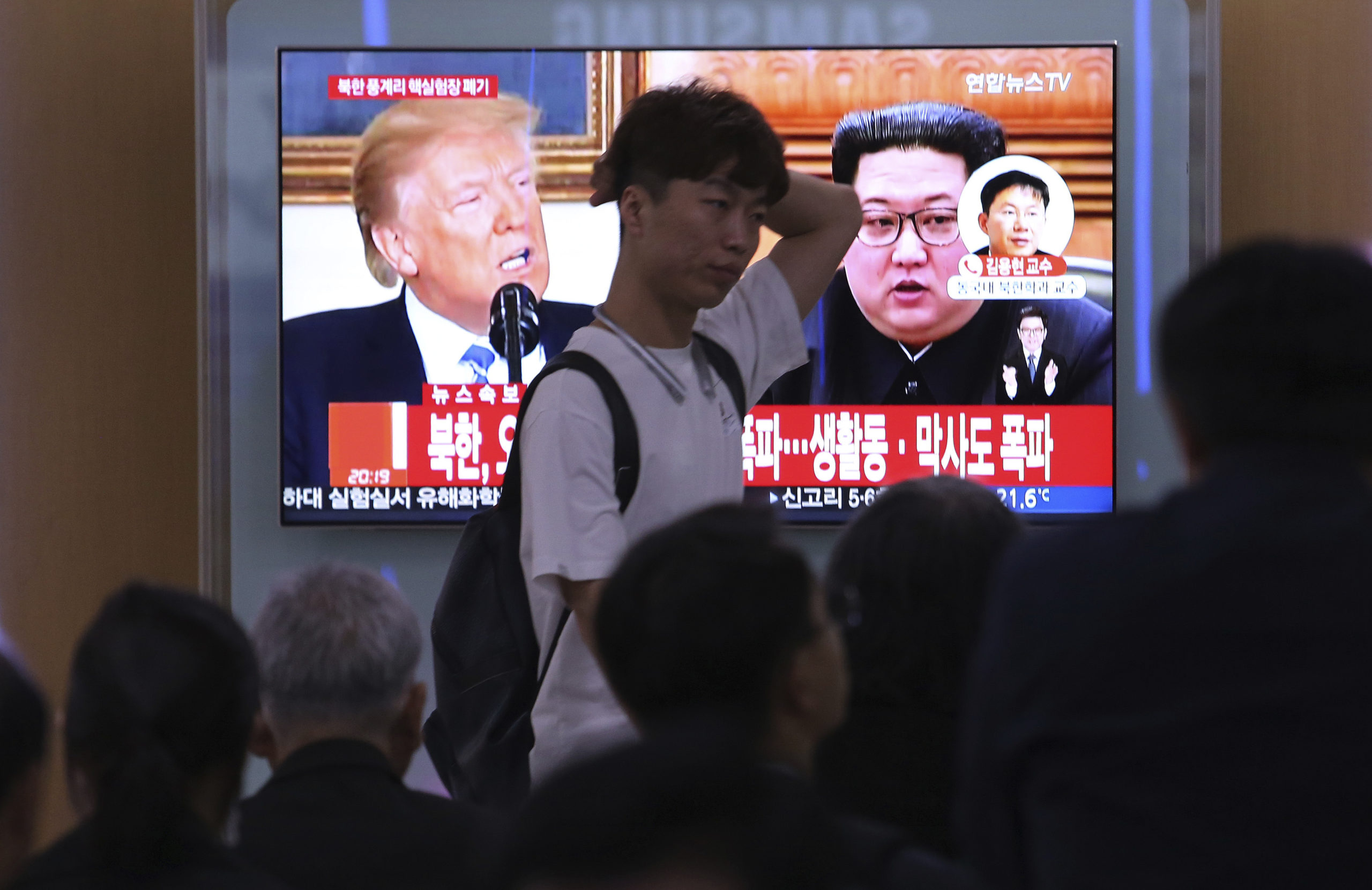 People watch a TV screen showing Donald Trump, left, and Kim Jong Un