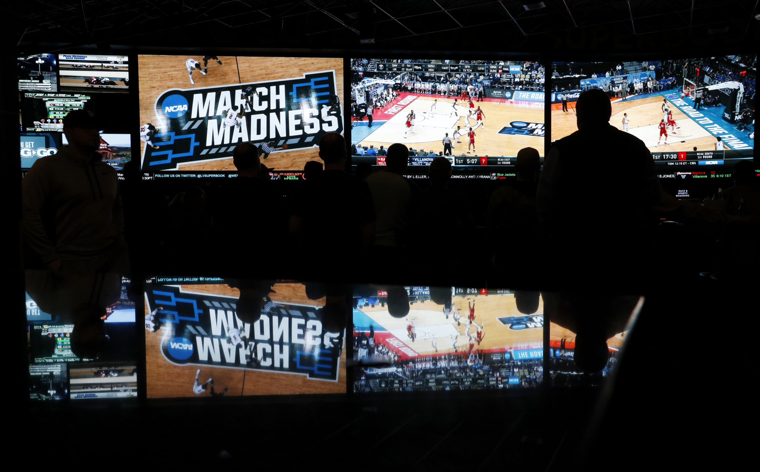 AP picture of people watching coverage of the first round of the NCAA college basketball tournament at the Westgate Superbook sports book in Las Vegas on March 15, 2018.