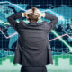 Picture of a man with his hands on head because he's puzzled by contradictory financial indicators