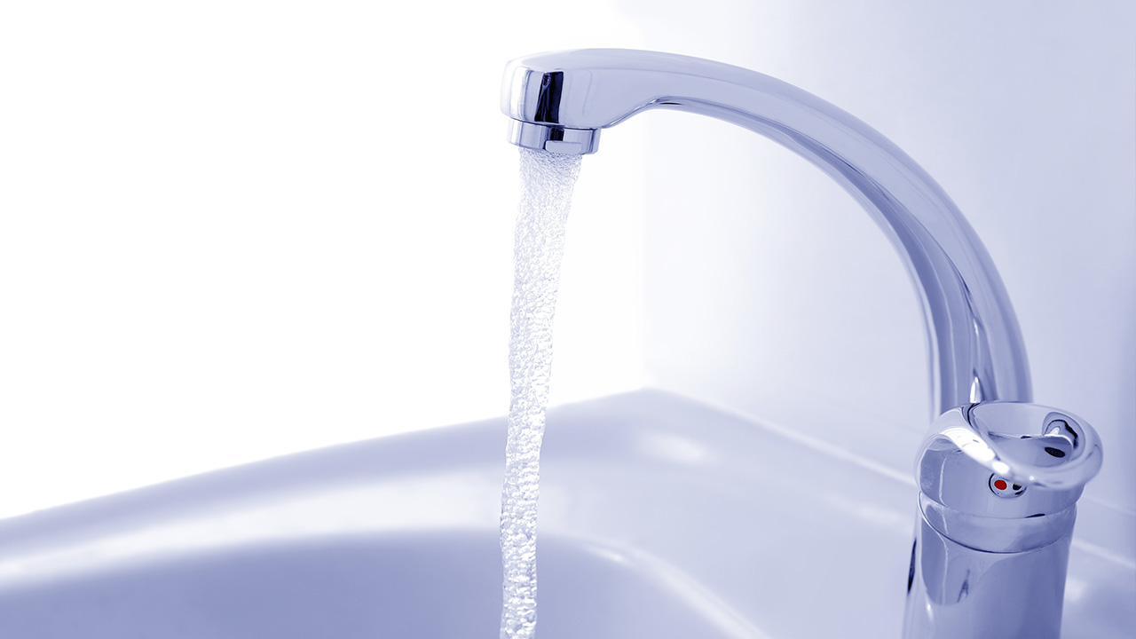 Water pours into a sink from a faucet