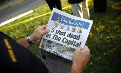 Photo of man reading Capital Gazette one day after a mass shooting at the newspaper