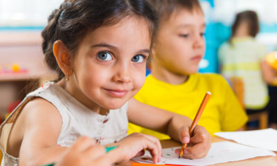 Photo of a girl and a boy at a table in a preschool room