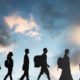 Image of immigrants in silhouette walking with luggage