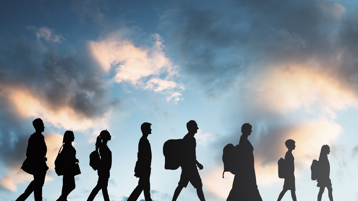 Image of immigrants in silhouette walking with luggage