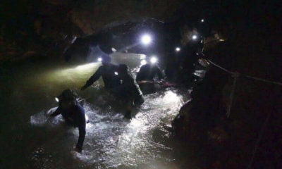 Rescue team in Thailand looking for young soccer players and their coach walk through a cave.