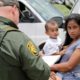 Photo of a mother and her child surrendering to U.S. Border Patrol agents