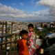 Rohingya children standing next to a bamboo fence