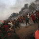 Photo of protesters running from tear gas at the Gaza Strip border