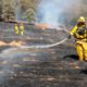 Photo of firefighters spreading water on smoldering spots
