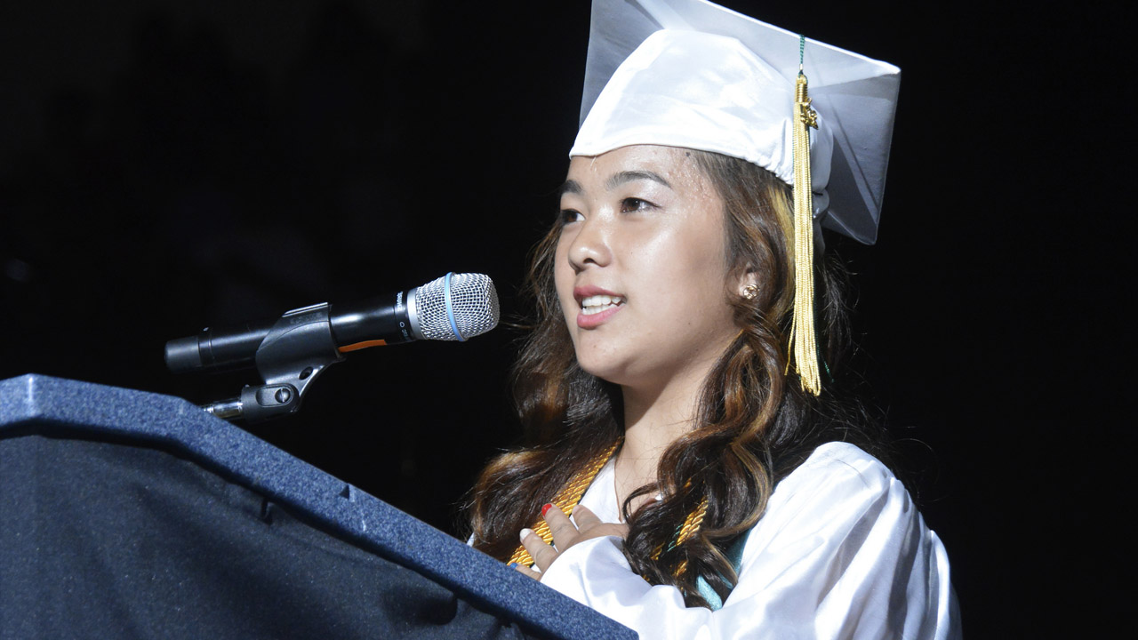 Fresno Unified School District Graduate in cap and gown speaking at commencement.