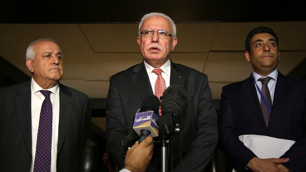 Photo of Riyad al-Maliki speaking to reporters