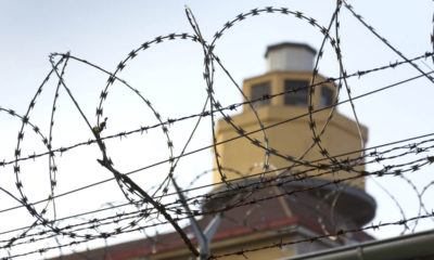 A prison guard tower viewed through razor wire fencing