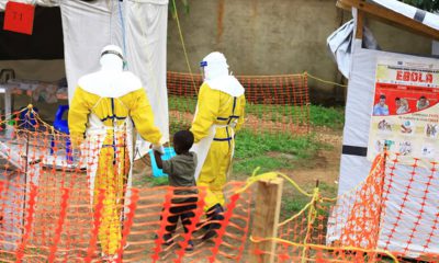 Photo of health workers walking with a boy that has ebola