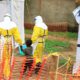 Photo of health workers walking with a boy that has ebola