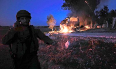 Photo of an Israeli soldier standing next to a burning bus