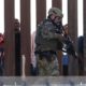 Photo of Border Protection officers walking along a wall at the border between Mexico and the U.S.