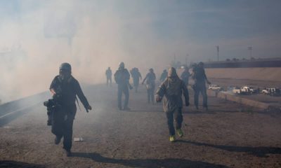 Photo of migrants running from tear gas