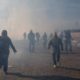 Photo of migrants running from tear gas