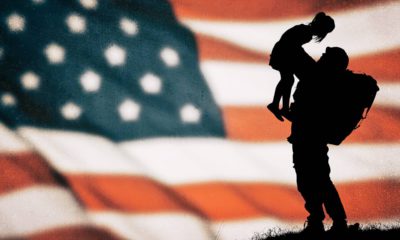 Photo of an American flag with a soldier and child silhouette