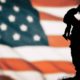 Photo of an American flag with a soldier and child silhouette