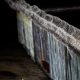 Photo of a boy looking at the border wall topped with razor wire