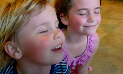 Young children cooling off in front of air conditioner.