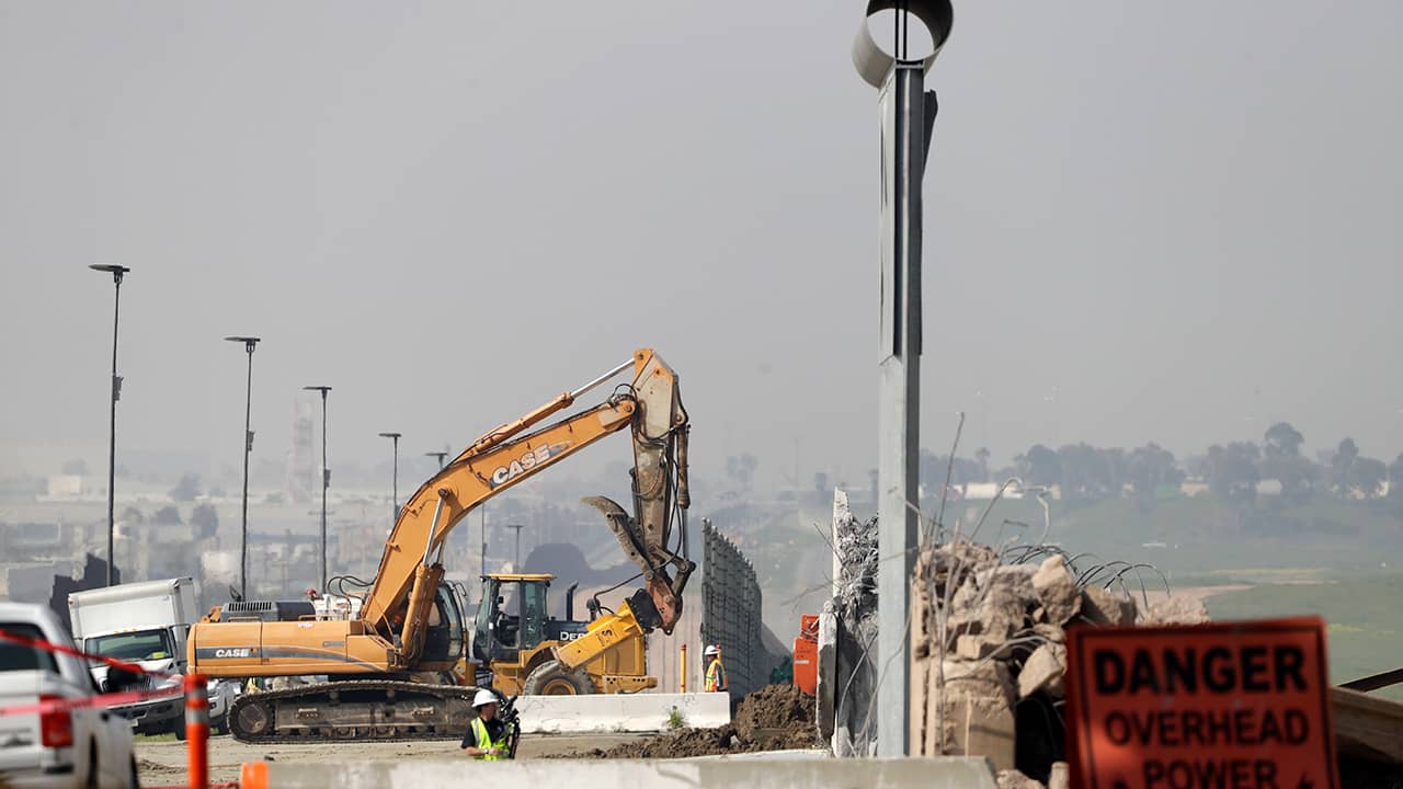 Photo of crews working to demolish border wall prototypes