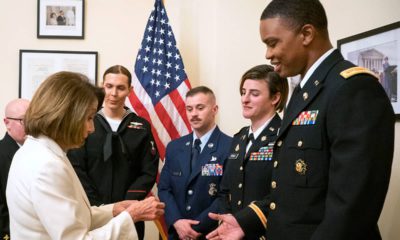 Photo of Nancy Pelosi giving challenge coins to military service members