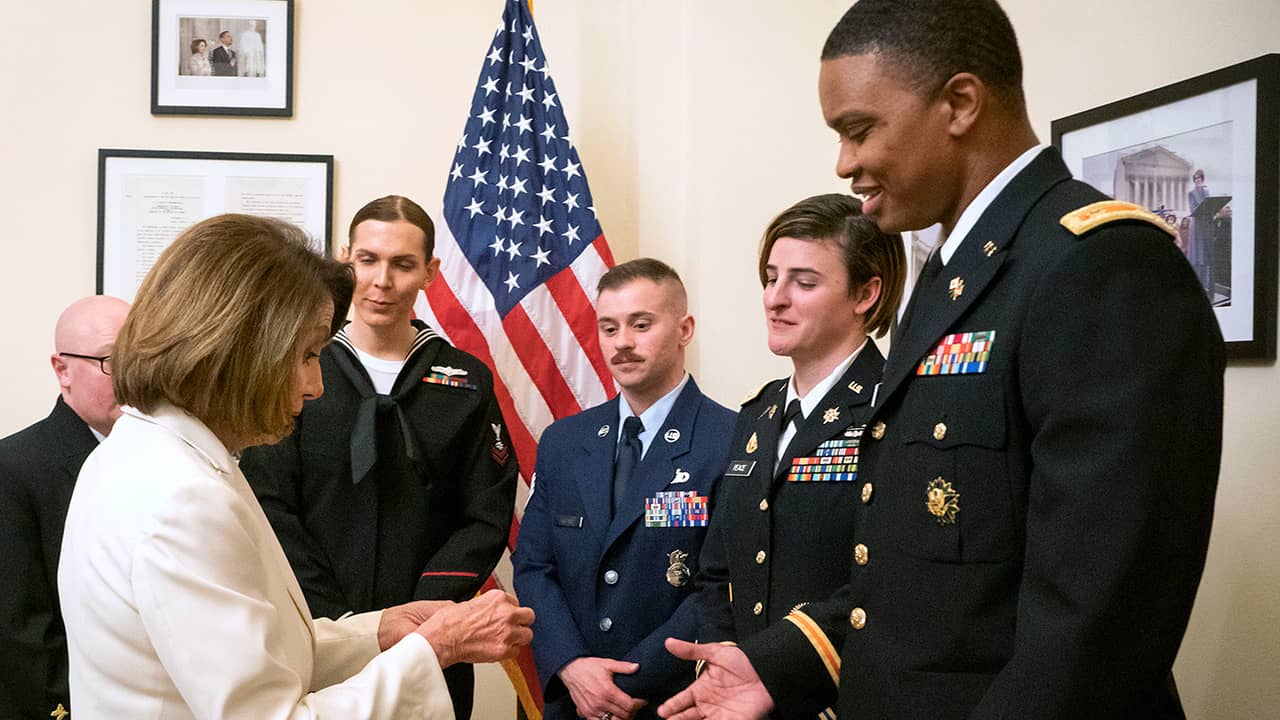 Photo of Nancy Pelosi giving challenge coins to military service members