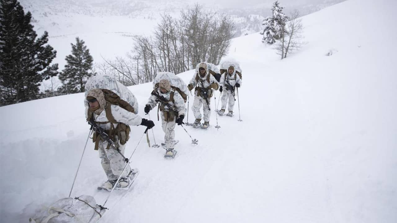 Photo of US Marines walking along a snow-covered trail