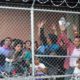 Photo of migrant families behind a barbed wire fence