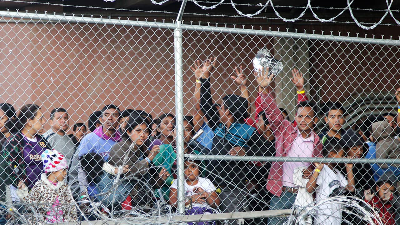 Photo of migrant families behind a barbed wire fence
