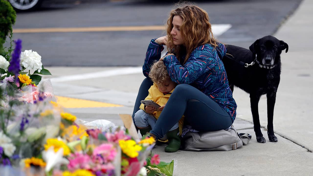 Photo of woman sitting at a memorial for the Chabad of Poway synagogue