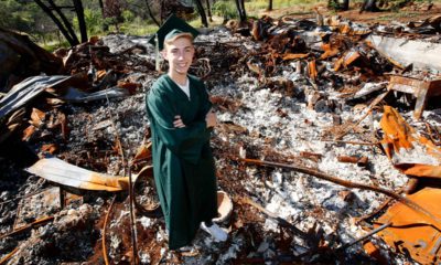 Photo of Sean Newsom posing at the burnout remains of his home in Paradise, CA