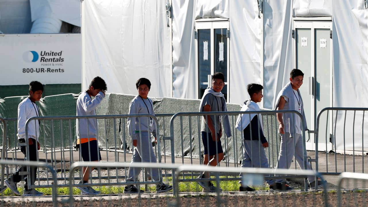 Photo of children lining up to enter a tent at the Homestead Temporary Shelter for Unaccompanied Children in Homestead, Fl.