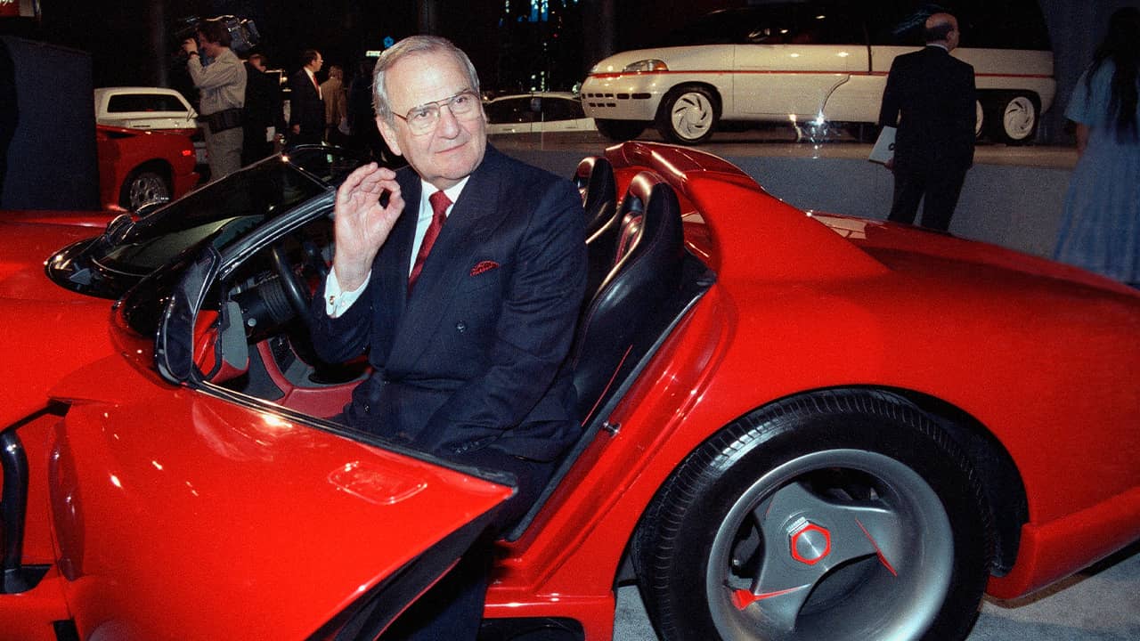 Photo of Lee Iacocca sitting in a 1990 Dodge Viper sports car in 1990
