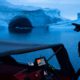 Photo of a boat navigating at night next to a large iceberg in Greenland