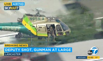 Photo of a sheriff's department helicopter with a sniper in an open door searching for a gunman at large