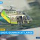Photo of a sheriff's department helicopter with a sniper in an open door searching for a gunman at large