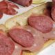 Photo of a man making a submarine sandwich with mortadella, cooked salami, ham, Genoa salami and sweet capicola