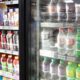 Photo of a shop owner reaching into a refrigerator