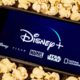 Photo of an iPhone with Disney Plus on the screen surrounded by popcorn