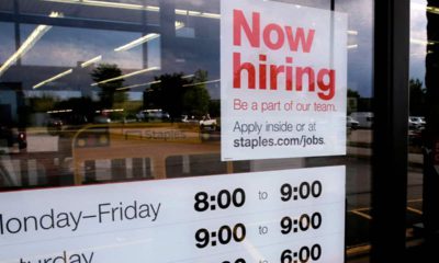 Photo of "Now Hiring" sign on the front door of a Staples store