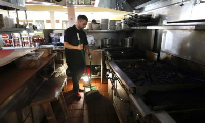 Photo of Salvador Espinosa sweeps in the kitchen of Mary's Pizza Shack