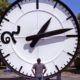 Photo of a man looking up at a big clock