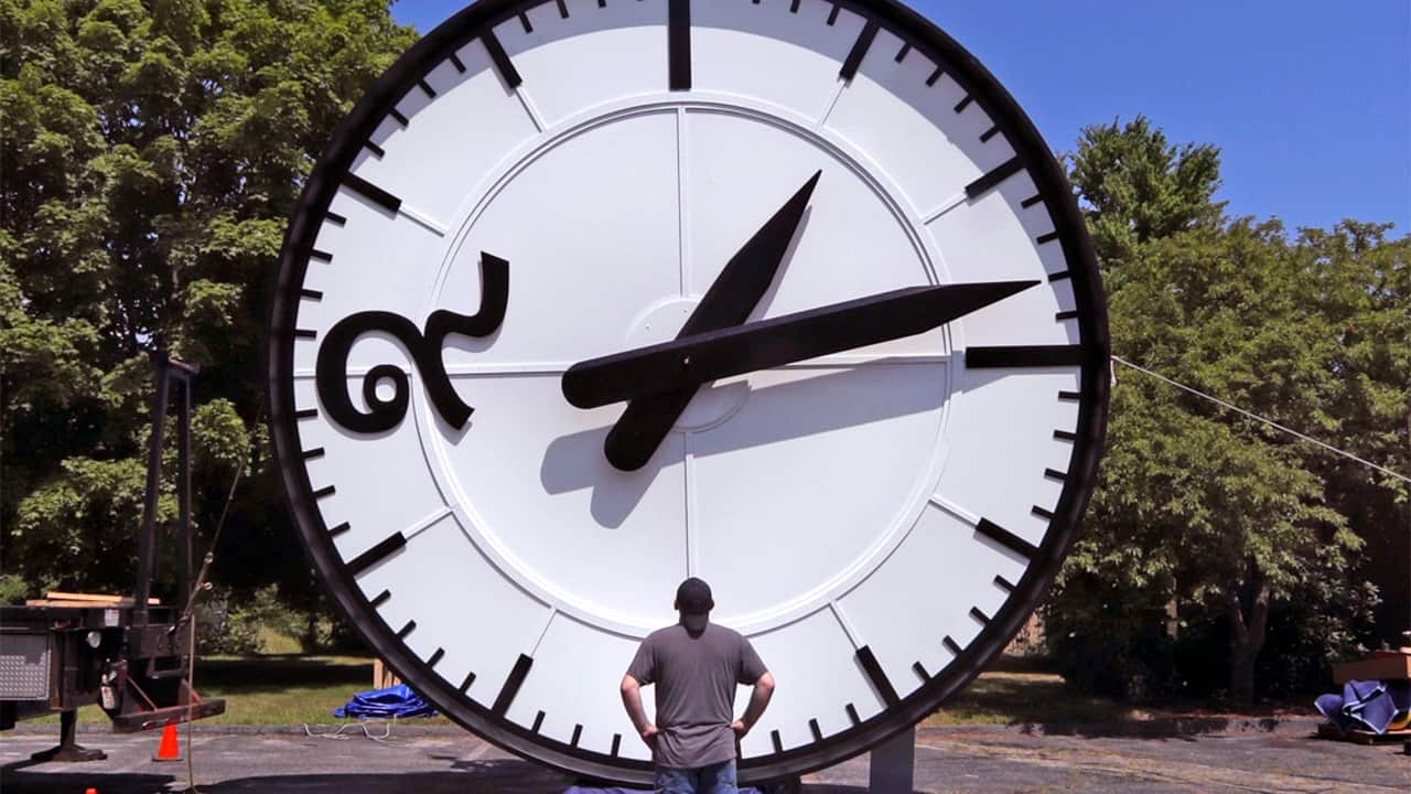 Photo of a man looking up at a big clock