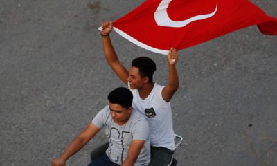 Photo of to men on a motorcycle holding the Turkish flag in the air