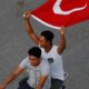 Photo of to men on a motorcycle holding the Turkish flag in the air